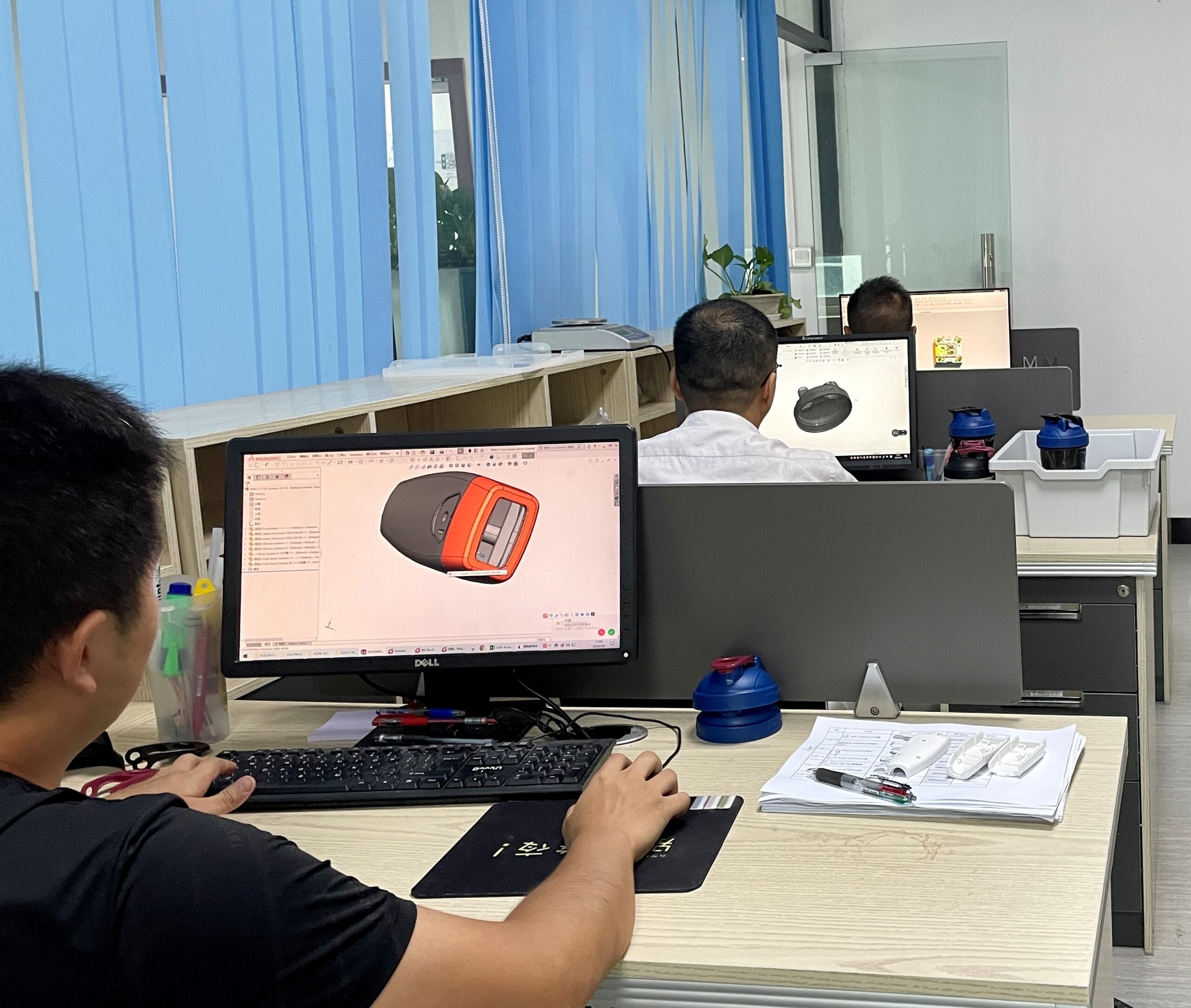 Engineer reviewing a product model and physical sample for manufacturability