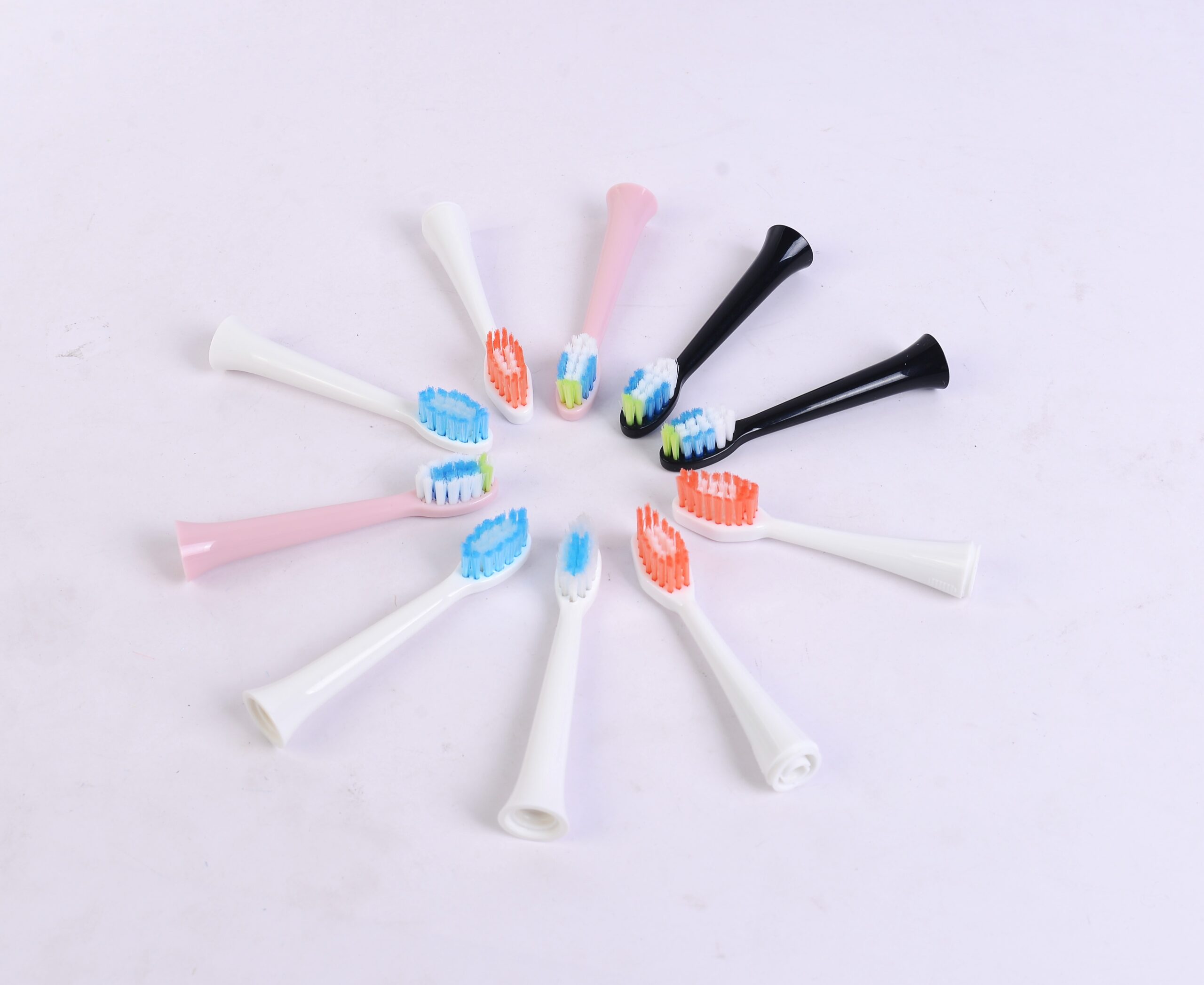 Electric toothbrush handles and replaceable brush-head samples in multiple colors.